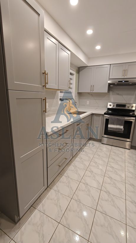 Grey shaker drawers and tall pantry with brass bar pulls