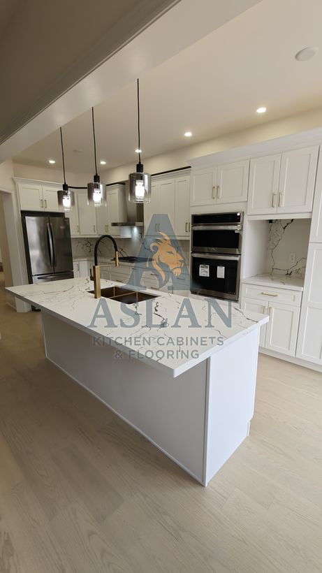 Marble-look quartz waterfall island with gold double sink in a white shaker kitchen
