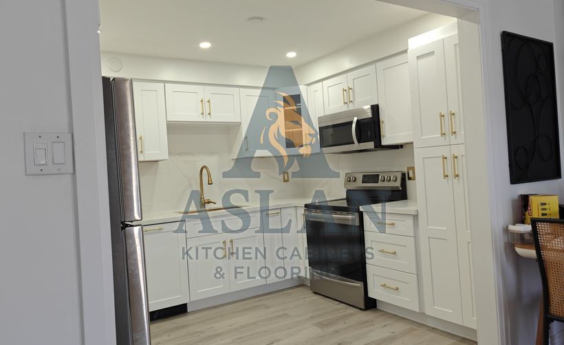 White shaker kitchen with brushed gold pulls and a quartz slab backsplash