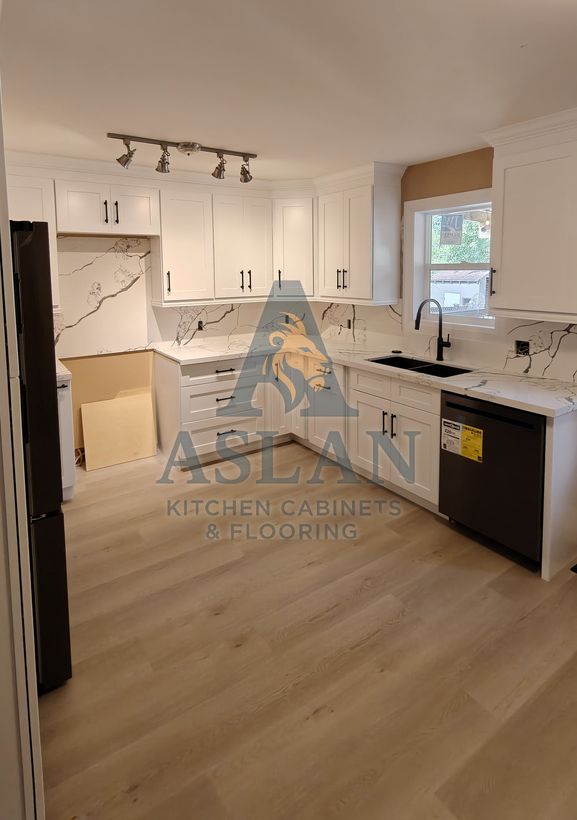 Finished white shaker L-shaped kitchen with marble-look backsplash, black sink and dishwasher, and light vinyl plank floor