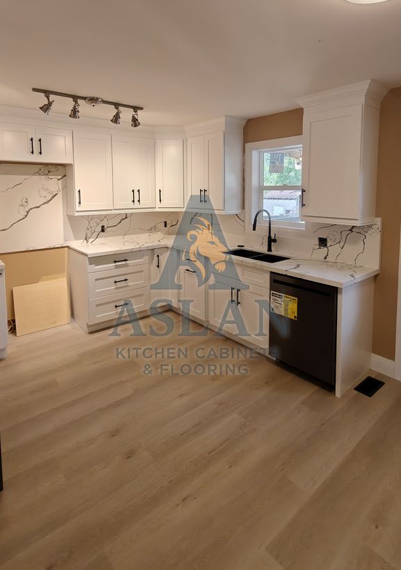 White shaker kitchen with crown moulding, marble-look quartz backsplash and under-window sink