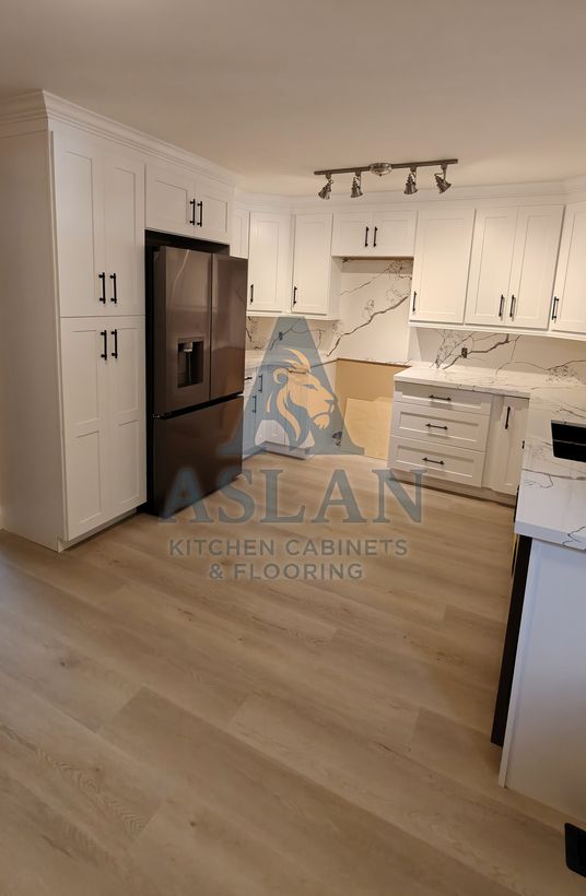 Floor-to-ceiling white shaker pantry cabinets beside a black fridge with matte black pulls