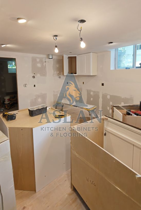 Kitchen cabinets being installed in a basement before countertops and backsplash