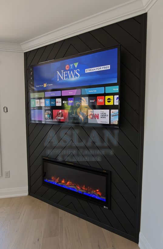 Side view of a black herringbone panel TV wall with a recessed electric fireplace